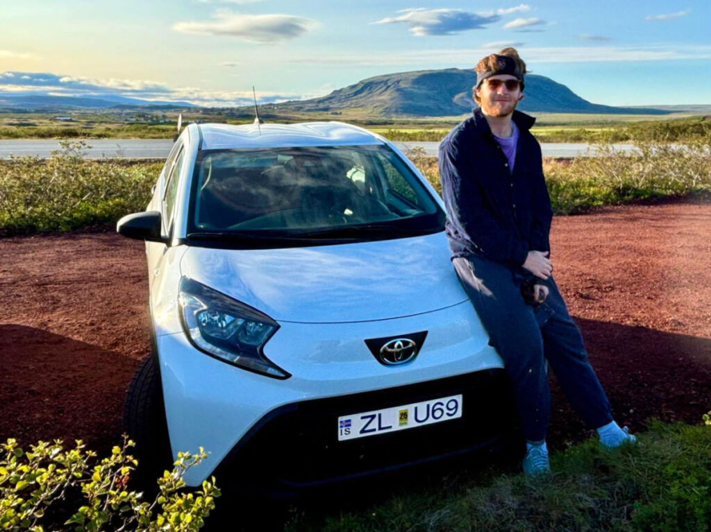 A man sitting on the hood of the Toyota Aygo