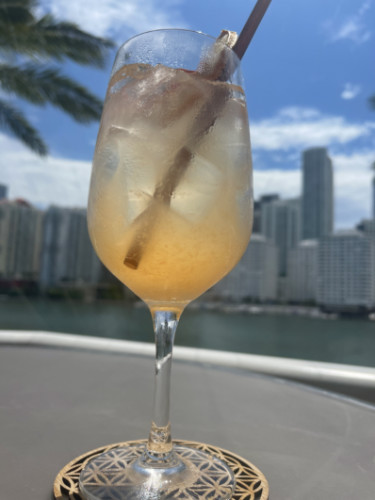 A cold drink on a table with Miami rooftop views in the background