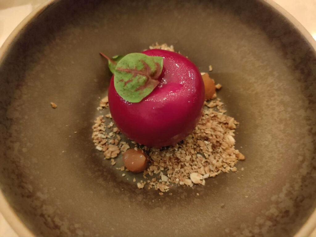 A “toffee apple” filled with mousse in a dark plate at Six by Nico