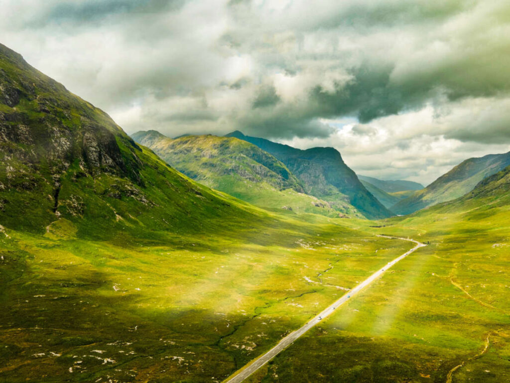 Picturesque view of the sun rays over the vast green landscape around the A82 route in Glencoe