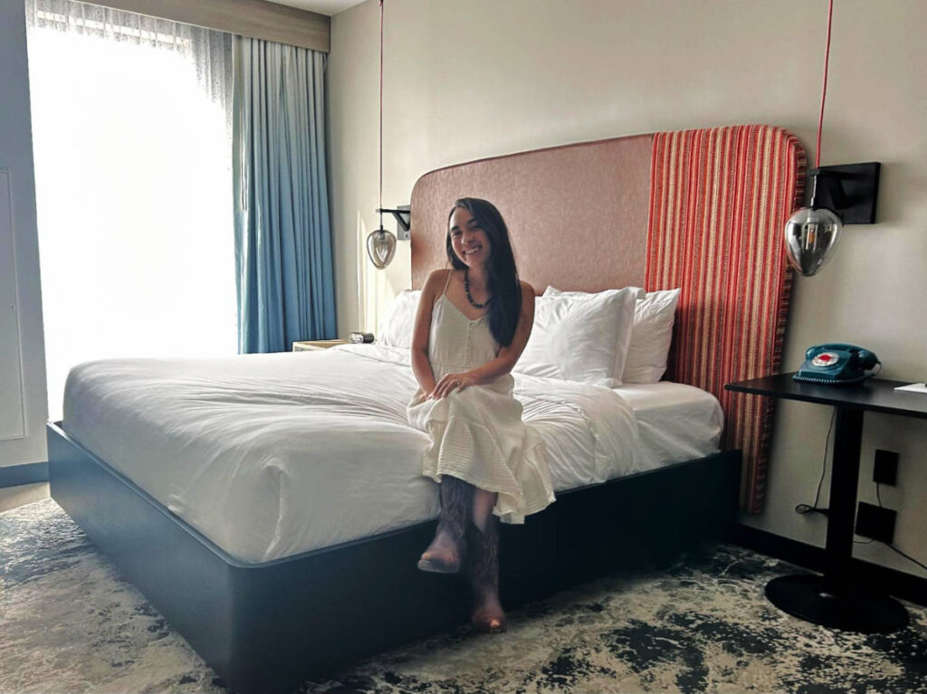 The author, Abigail Bliss sitting on their bed at Hotel Indigo