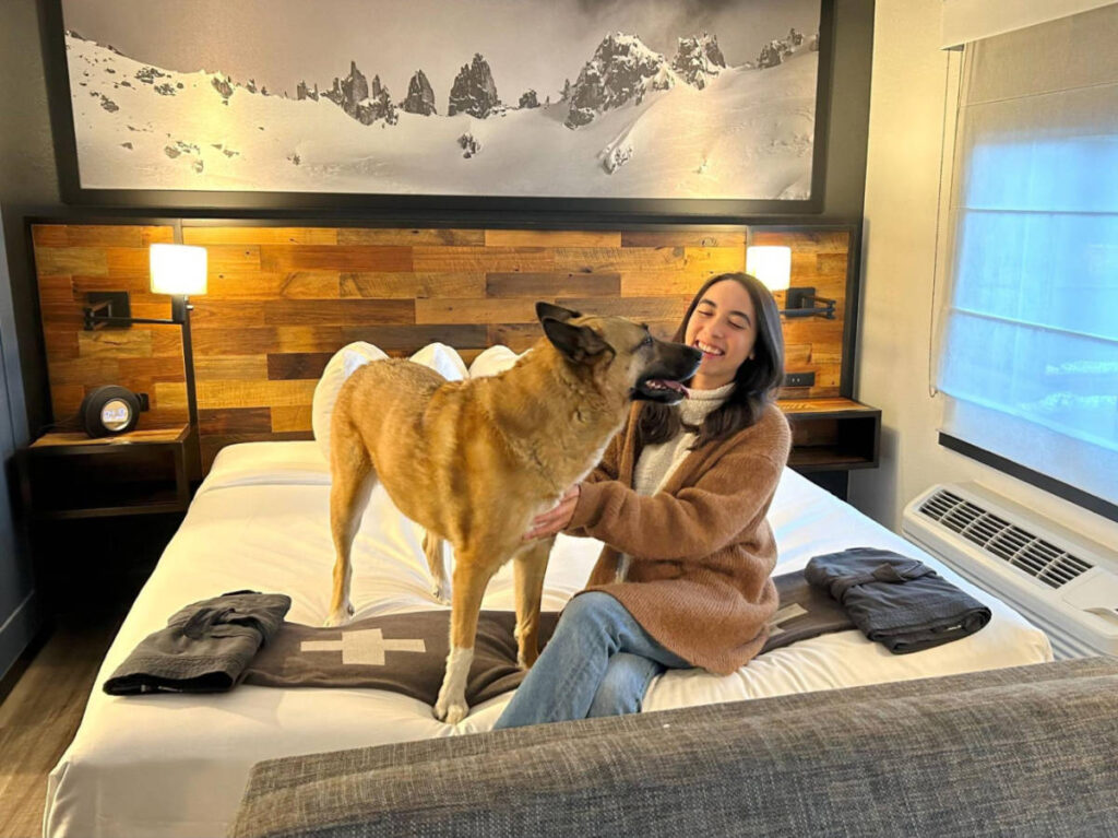 Travel Lemming writer Abigail Bliss and her dog sitting on the huge bed in Gravity Haus