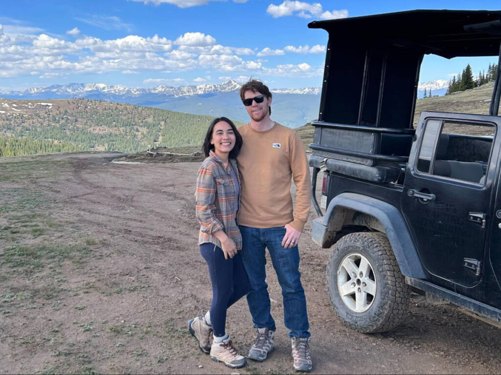 The author Abigail Bliss and her husband, posing for a photo with an overlooking view on the mountain