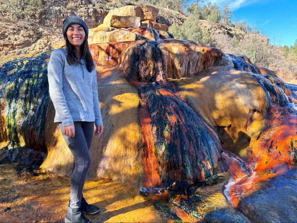 The author Abigail Bliss, standing next to the huge rocks at Pinkerton Hot Springs