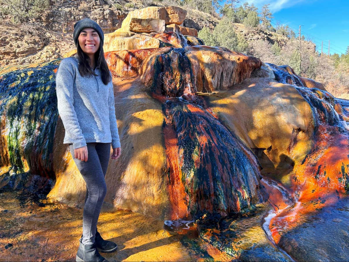 The author Abigail Bliss, standing next to the huge rocks at Pinkerton Hot Springs