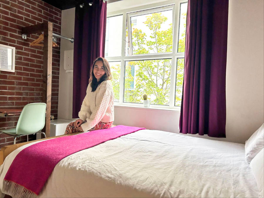 The author Abigail Bliss sitting on the bed inside the room of The Nest Boutique Hostel