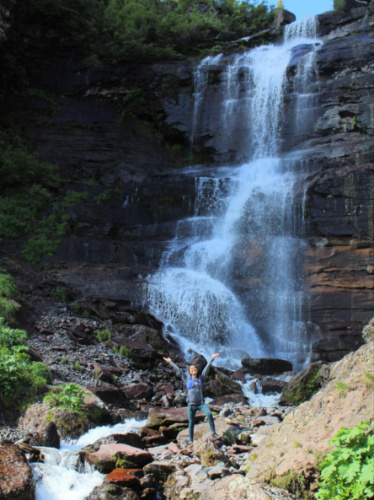 Travel Lemming Editor Abigail Bliss smiling for a photo at the base of the waterfall