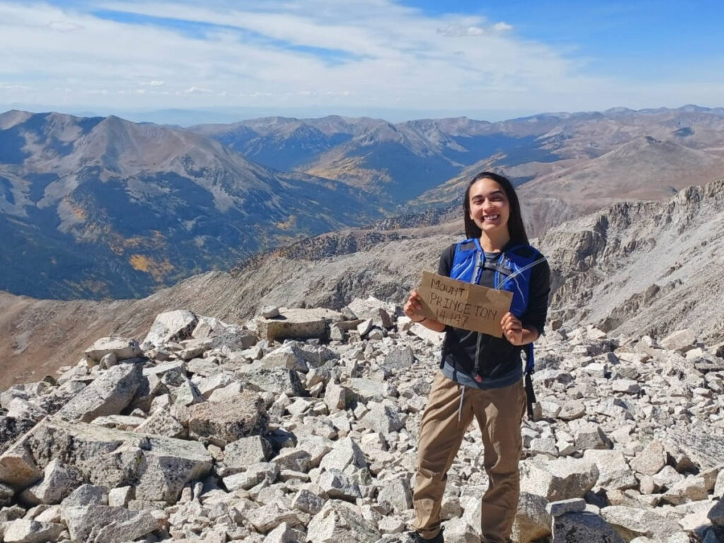 The author Abigail Bliss, holding a signage at the top of Mt. Princeton
