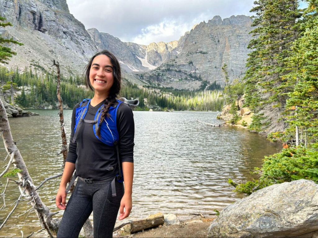 Travel Lemming editor Abigail standing near a lake while hiking in Rocky Mountain National Park