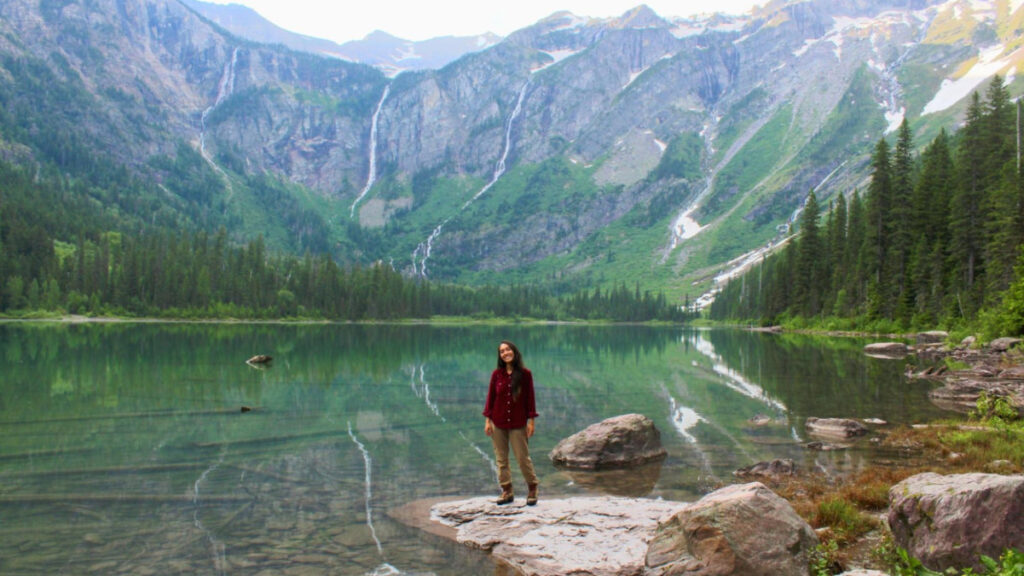Abigail in Glacier National Park, with a lake and mountains in background