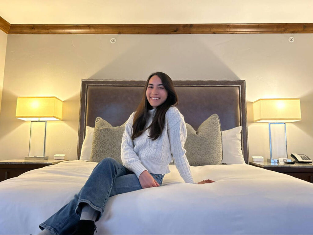 The author Abigail Bliss, sitting on the bed in the hotel room of The Sebastian