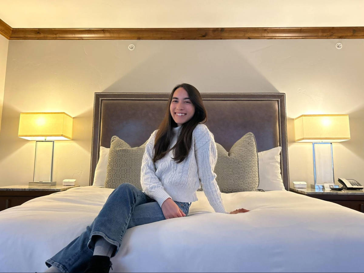 The author Abigail Bliss, sitting on the bed in the hotel room of The Sebastian