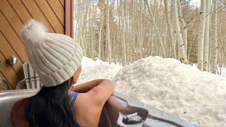 Travel Lemming Editor Abigail Bliss, enjoying the snowy view from the hot tub at a Frisco townhouse rental