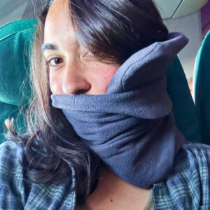 The author Abigail Bliss using the trtl Travel Pillow in the plane