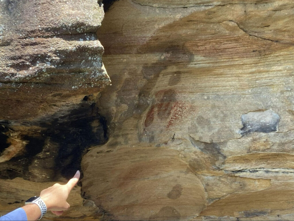 A person pointing to the Aboriginal Rock Art near West Head Lookout