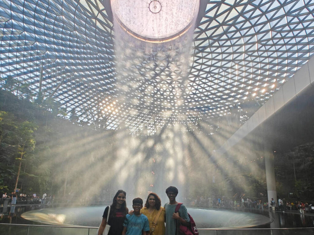 The author Advaita and her family, smiling in front of the Jewel Vortex at the Changi Airport