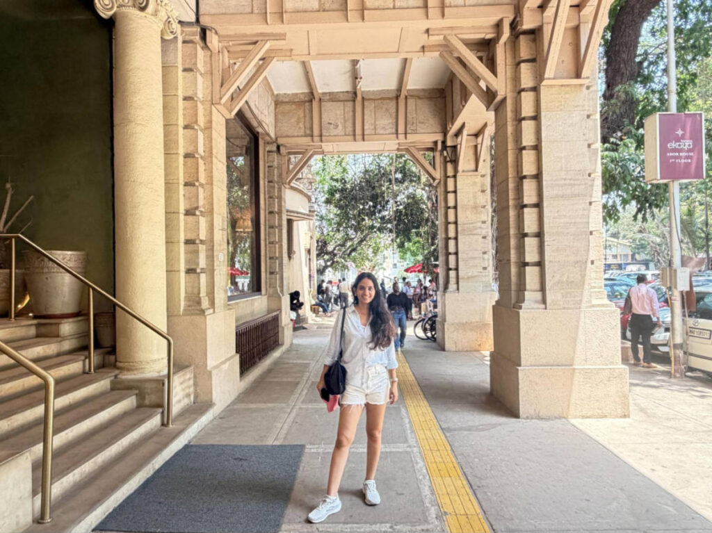 The author Advaita, smiling for a photo at the colonnaded walkway of Ador House