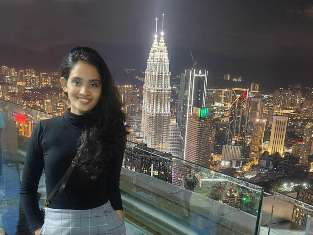 The author, Advaita, posing for a photo with an overlooking view of the city center and Petronas Towers at night