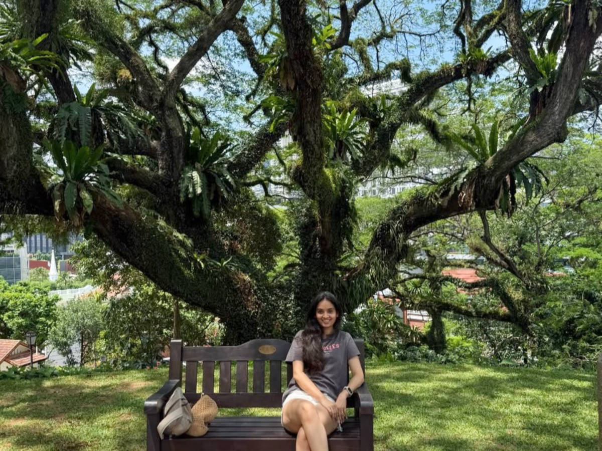 The author Advaita, sitting on a bench at the heritage Raintree in Fort Canning Park