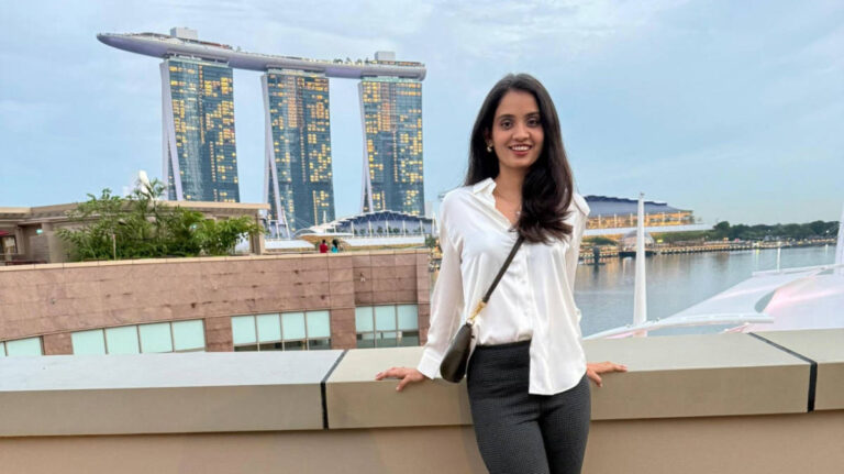 The author Advaita, posing for a photo with the view of Marina Bay Sands hotel from the Baia bar in Esplanade Mall