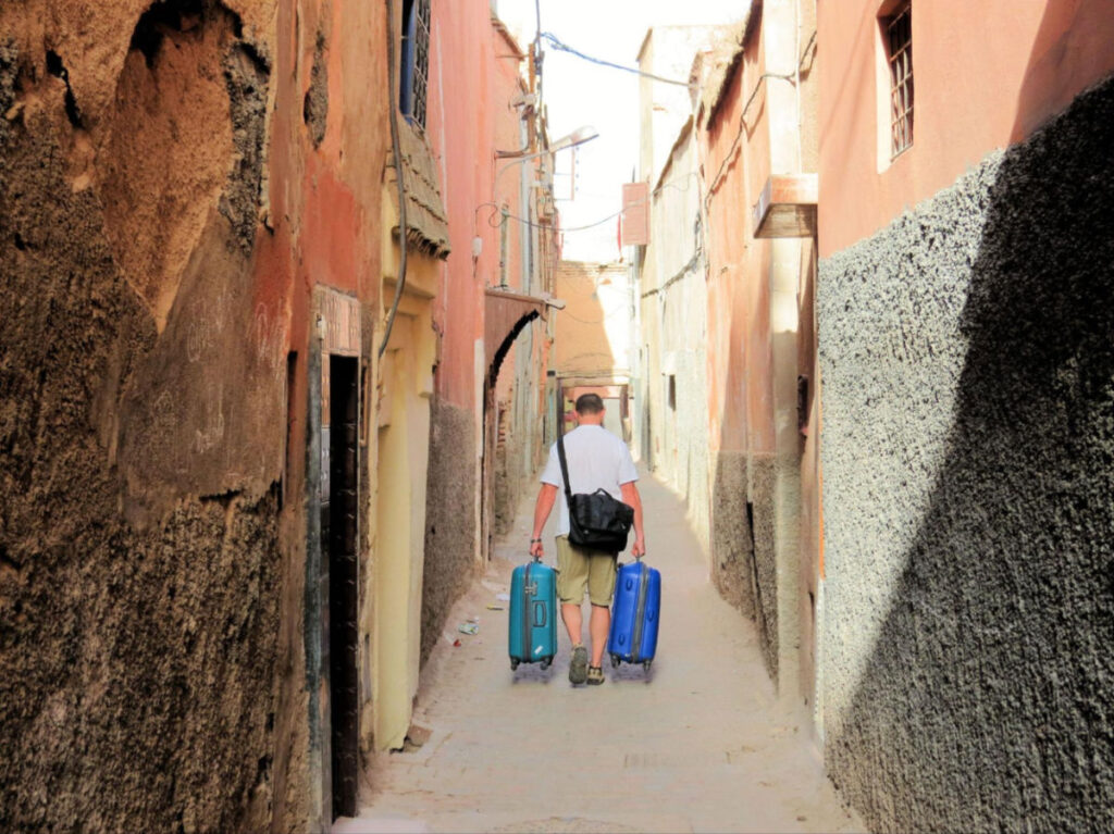 The author's husband carrying our suitcases down a narrow alleyway in the Mellah neighbourhood
