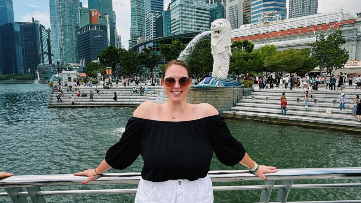 The author Allie Hubers, posing for a photo with the Merlion in the background