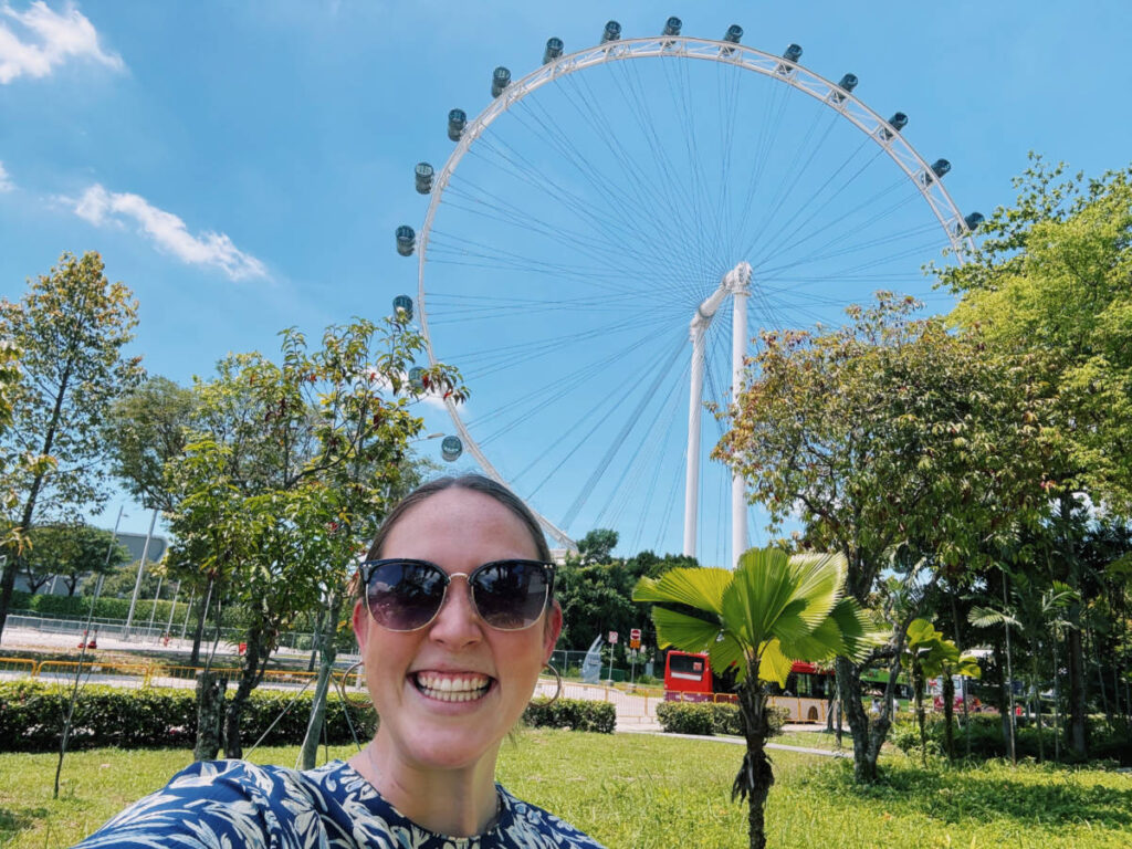 The author Allie Hubers smiling for a photo with the view of Singapore Flyer in the background