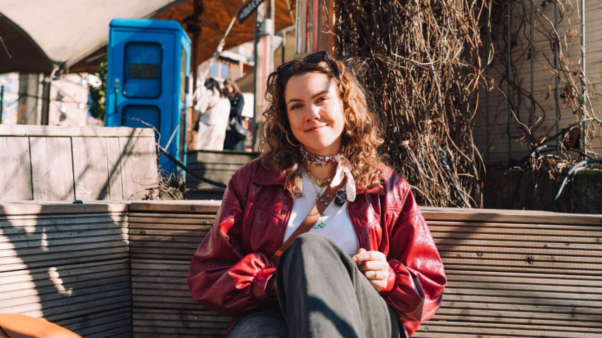 The author Amber Visch, sitting on a bench in Berlin on a sunny day