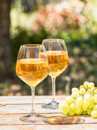 Two glasses of amber wines on an outdoor table