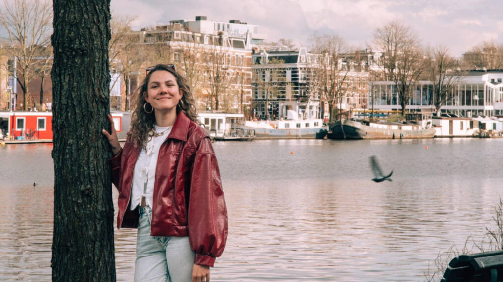 The author Amber Visch posing for a photo with the river Amstel in the background