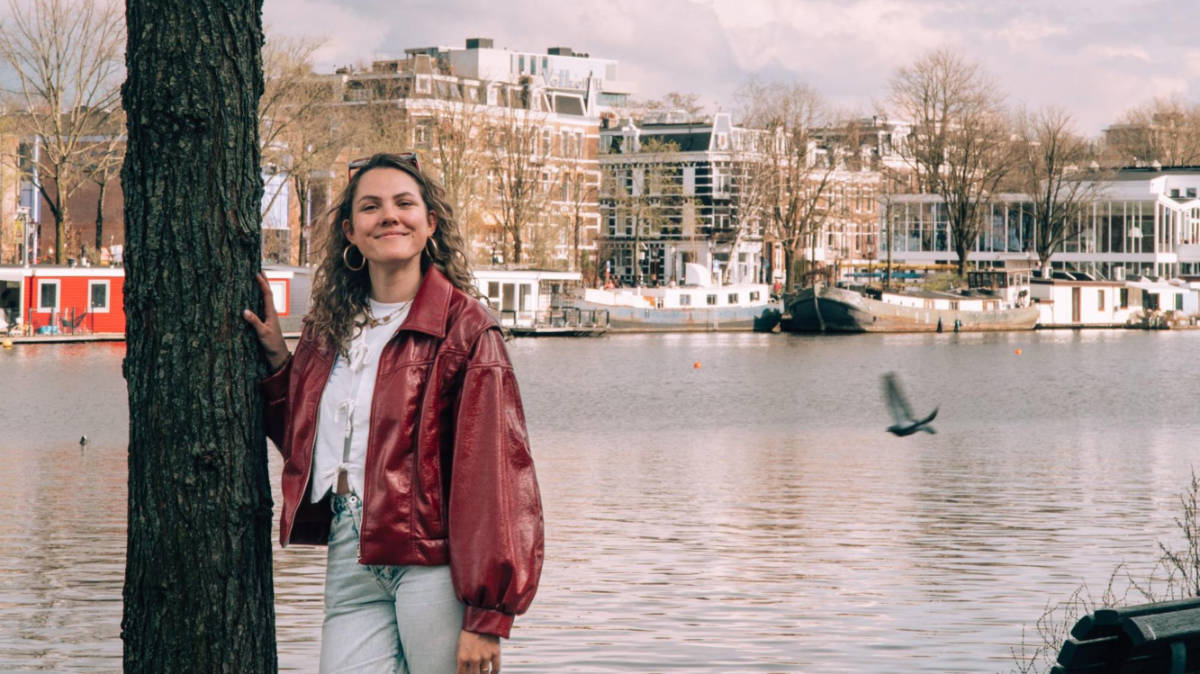 The author Amber Visch posing for a photo with the river Amstel in the background
