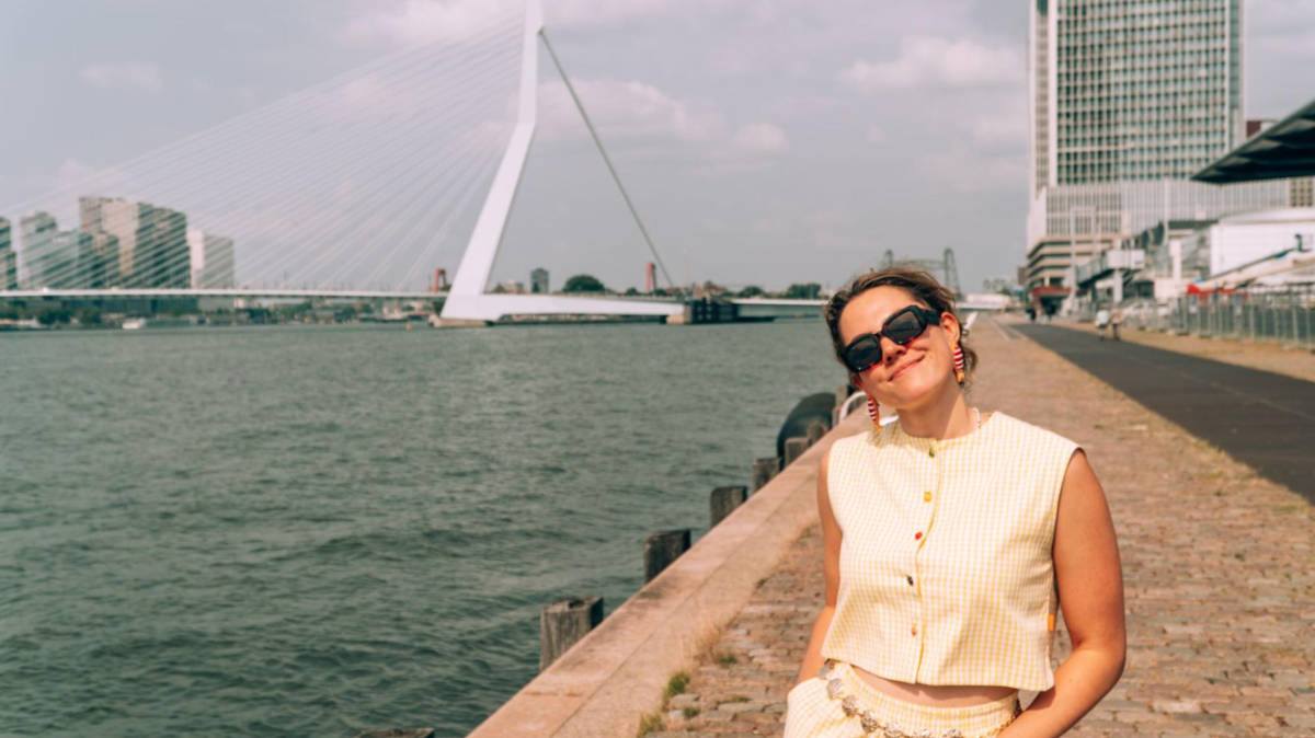 The author Amber Visch, posing for a photo with the view of Erasmusbrug