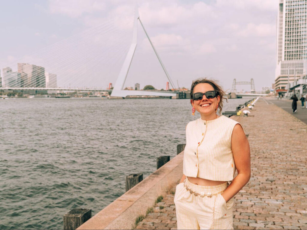 The author Amber Visch posing for a photo in front of the Erasmus Bridge