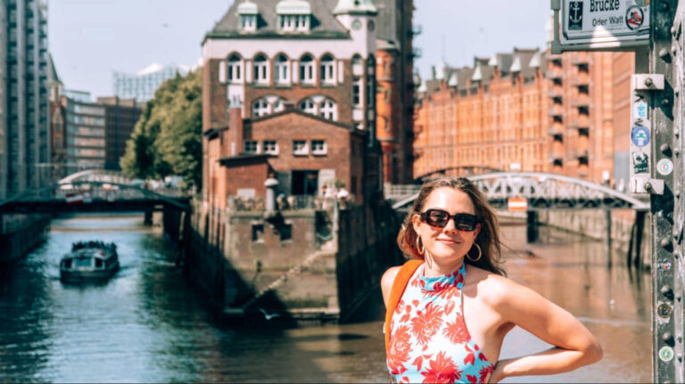 The author Amber Visch, smiling for a photo with the Speicherstadt canals in the background