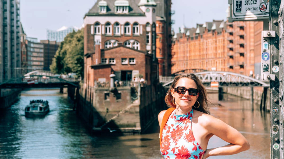 The author Amber Visch, smiling for a photo with the Speicherstadt canals in the background