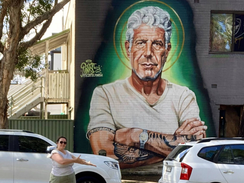 The author Ann-Marie Cahill, posing in front of the mural of Anthony Bourdain