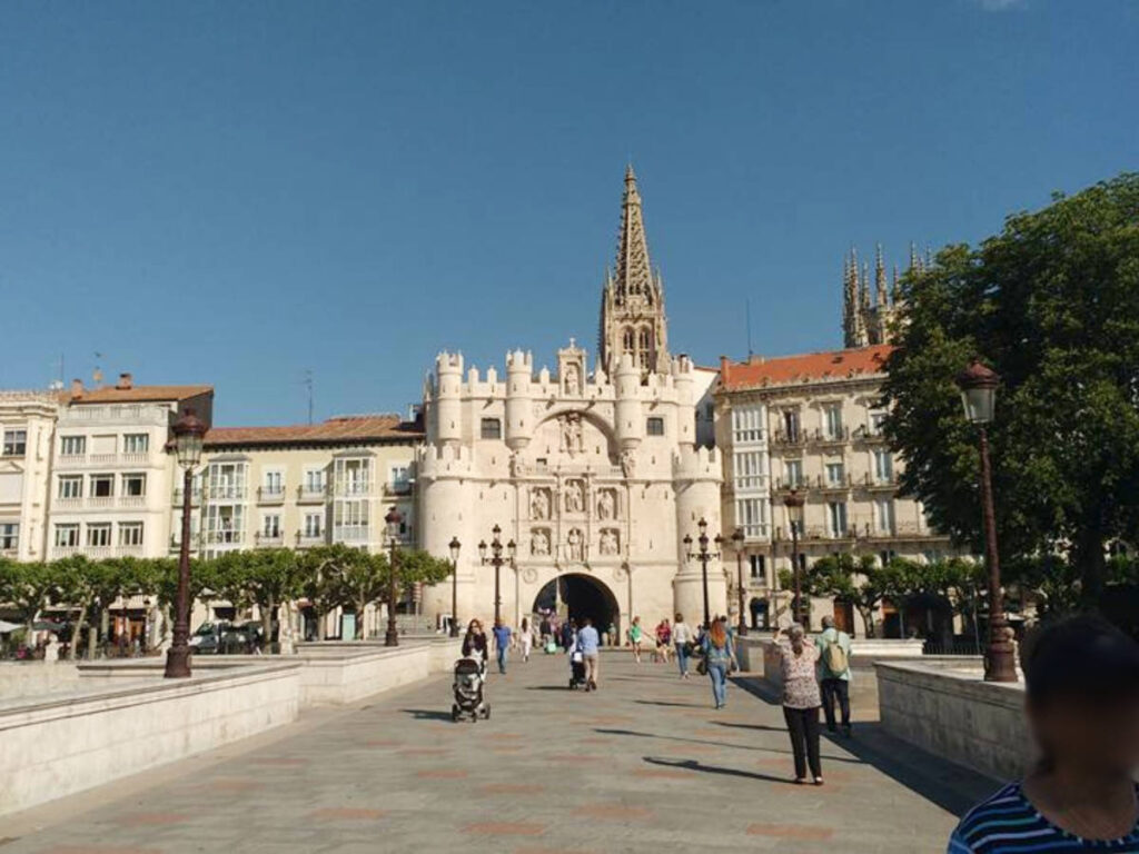 People walking along a wide pathway leading to the Puente and Arco de Santa María