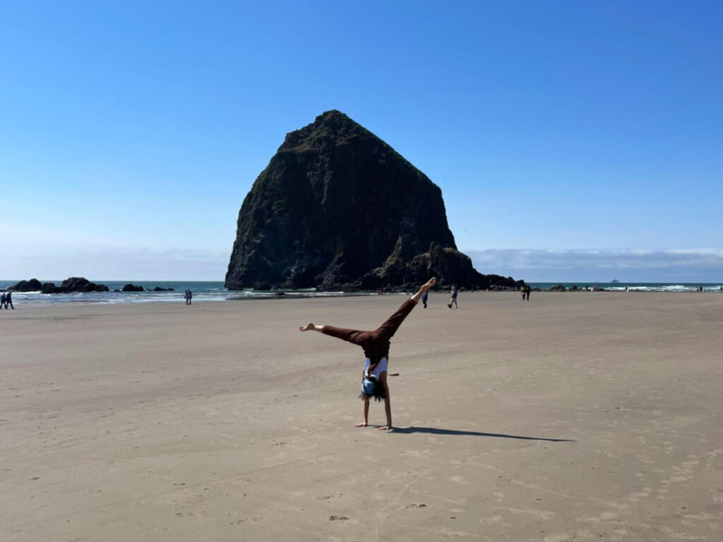Author Lea Rose Allbaugh cartwheeling on Cannon Beach