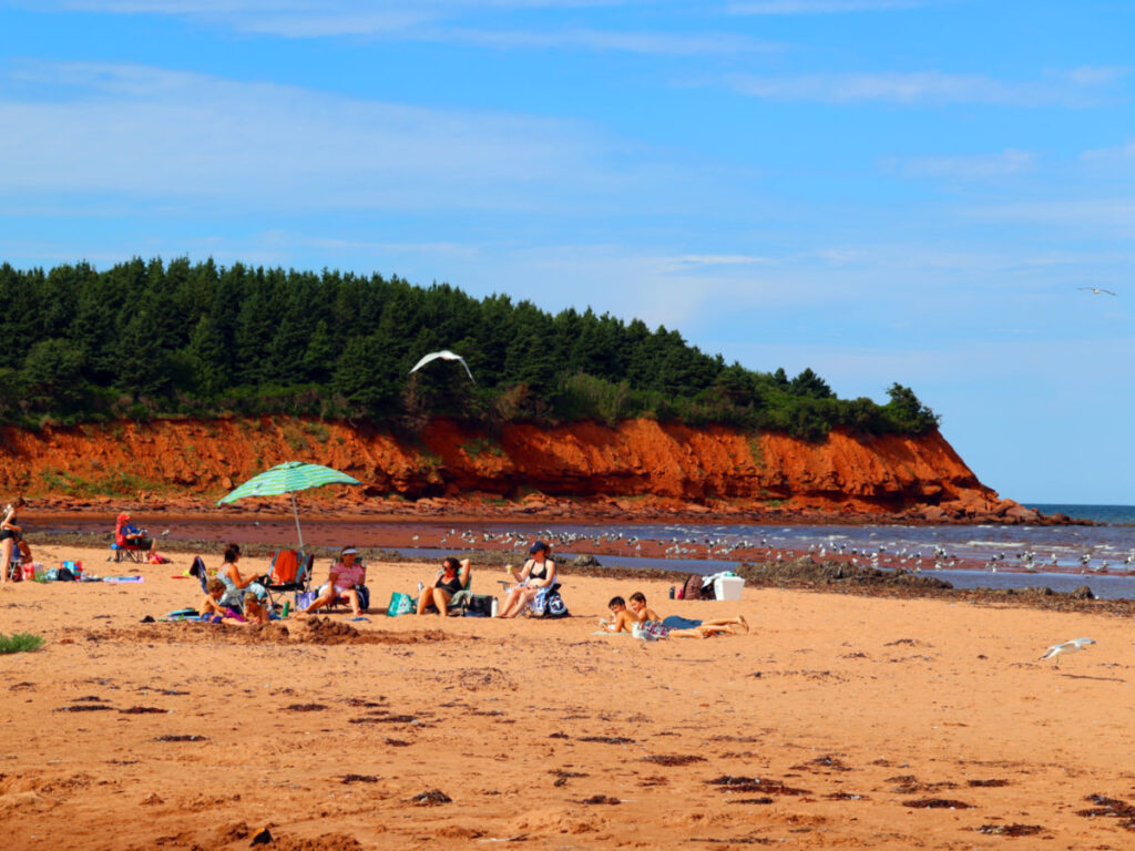 People relaxing at Cavendish Beach on a sunny day