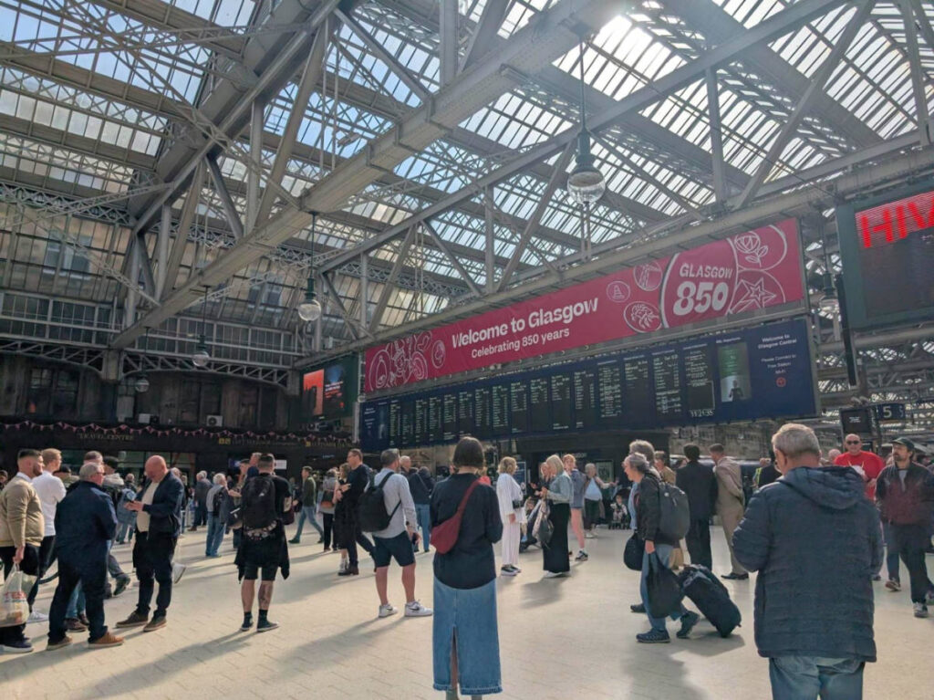 View of a crowded Glasgow Central Station and a view of the departure board