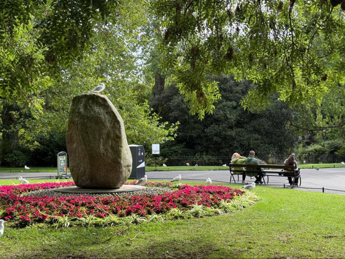 A large rock surrounded by birds and people relaxing at St. Stephen’s Green
