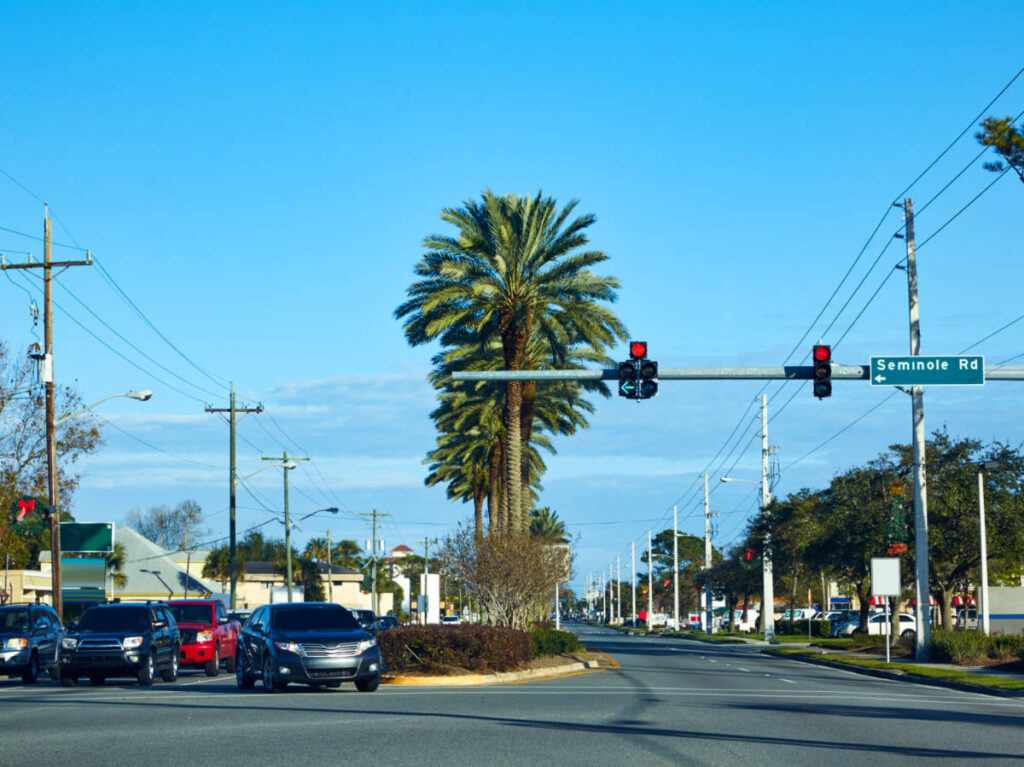 The cars on traffic at the road surrounded by palm trees in Atlantic Beach