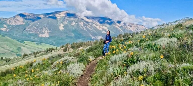 The author Abigail Nueve posing in the middle of the Colorado mountains with valleys in the background while hiking