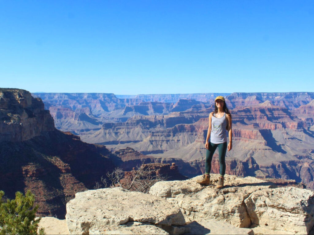 Author Abigail standing at the South Rim with a view of the Grand Canyon in the background
