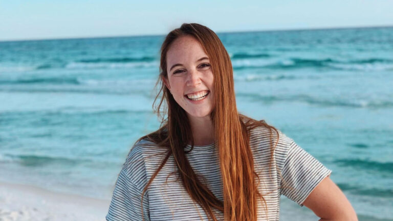 Author Allie smiling brightly on a beach in Destin