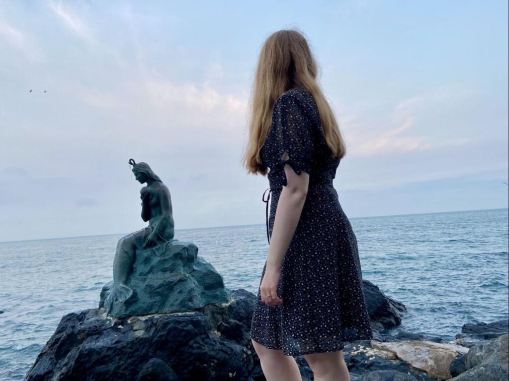 Author Bethan looking at the mermaid statue along the coastal trail on Dongbaekseom Island