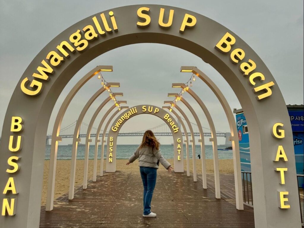 The author Bethan Nutting at the arch sign in Gwangalli Beach with Gwangan Bridge view