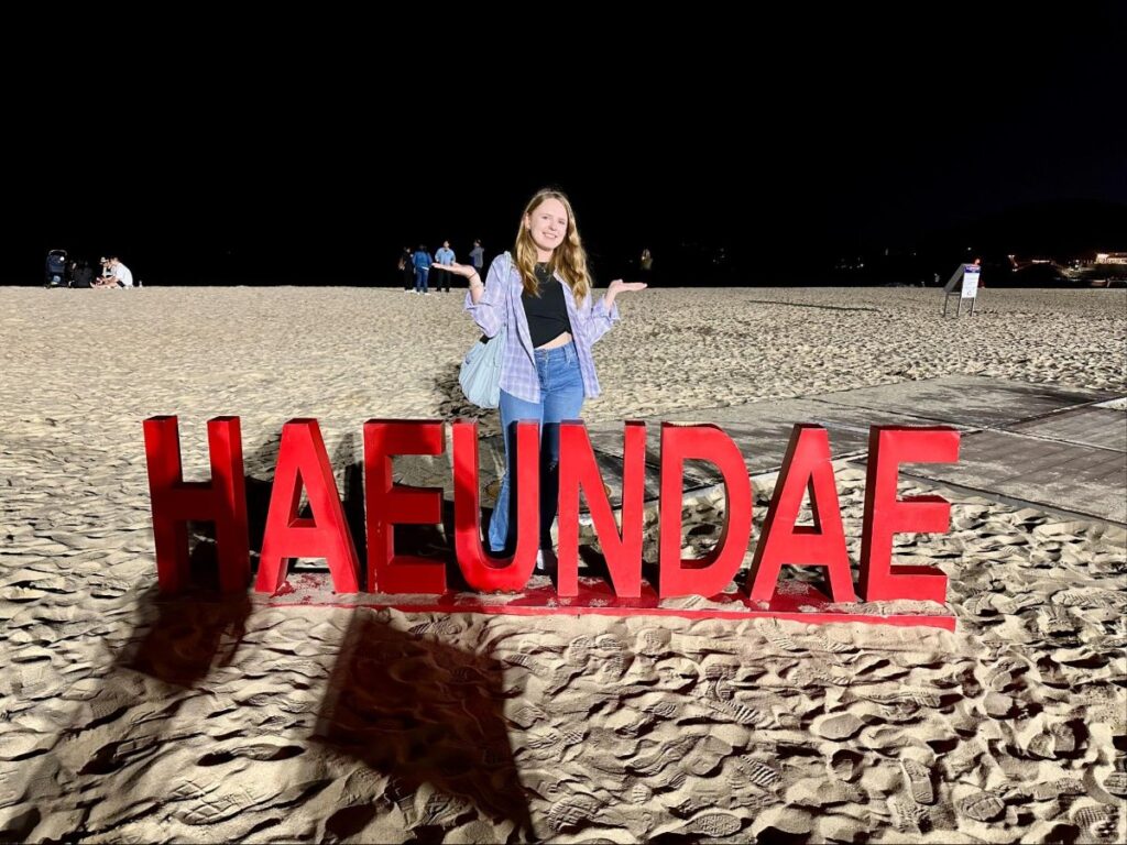 Author Bethan posing for a photo at the Haeundae sign at Haeundae Beach