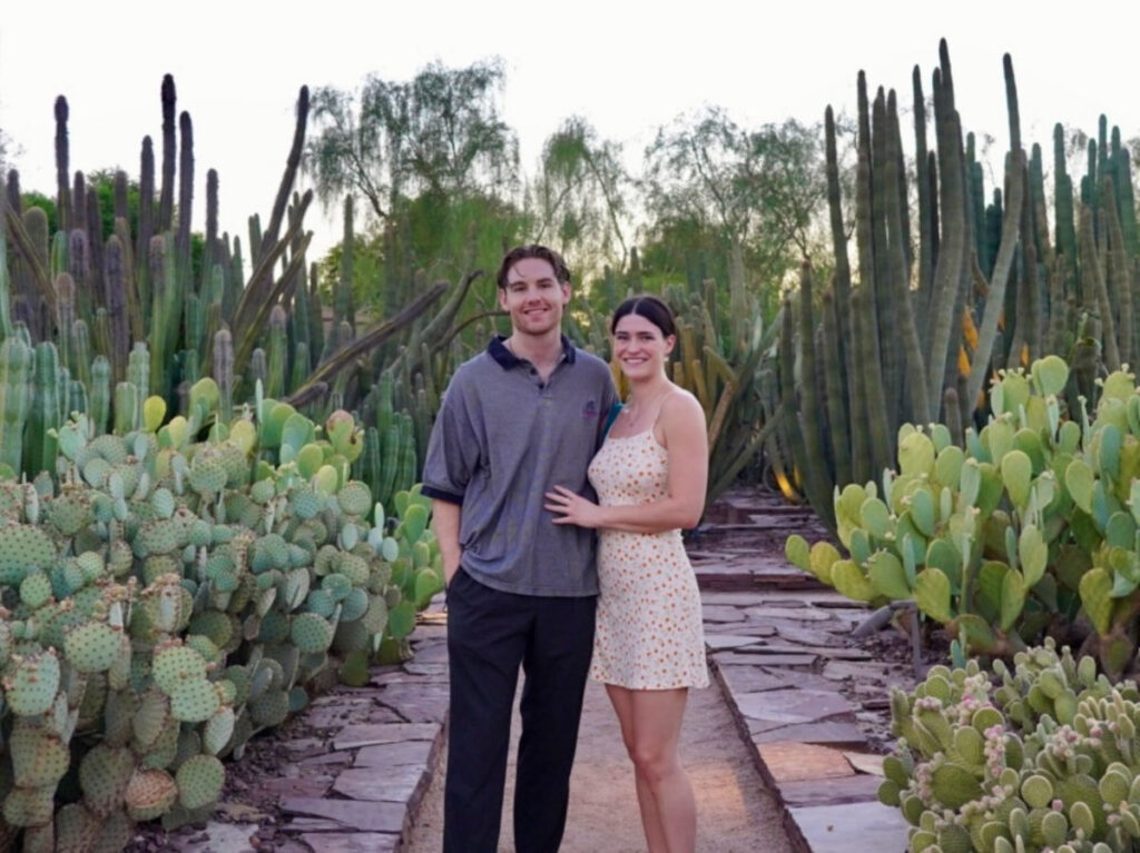 Author Betty and her boyfriend standing in the middle of the cacti at Desert Botanical Gardens