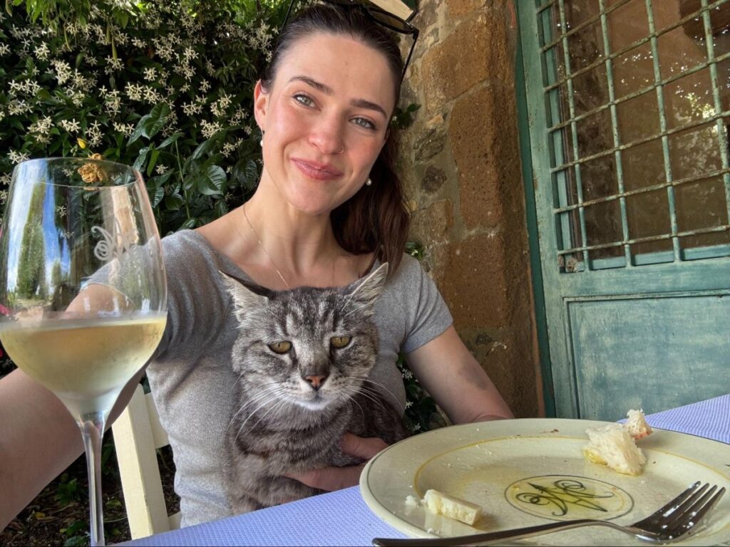 Author Betty wine tasting while holding a cat at Madonna del Latte vineyard
